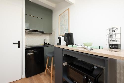 - une petite cuisine avec un comptoir et un tabouret dans l'établissement Ô Saint-Michel - studio climatisé à 200 m du métro, à Toulouse