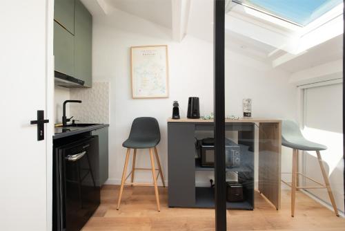 Il comprend une petite cuisine avec un bureau et deux chaises. dans l'établissement Ô Saint-Michel - studio climatisé à 200 m du métro, à Toulouse