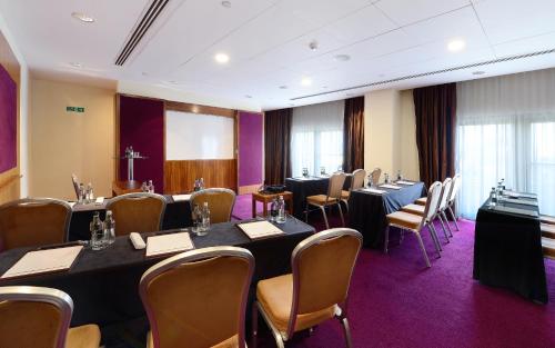 a conference room with tables and chairs and a screen at Canary Riverside Plaza Hotel in London