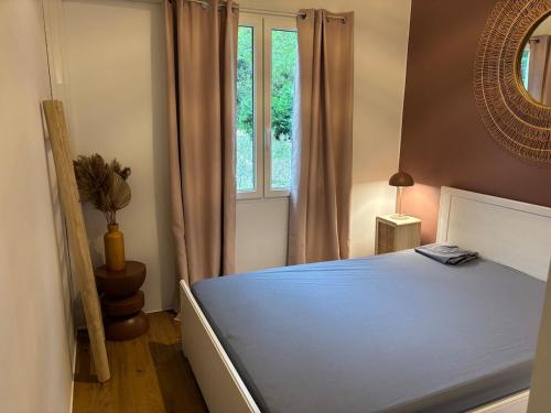 a bedroom with a blue bed with a window at Gite Cocon entre lac et Nature in Carcassonne
