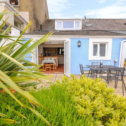 a blue house with a patio and a table at Characterful and quirky cottage in beautiful Pembs in Fishguard