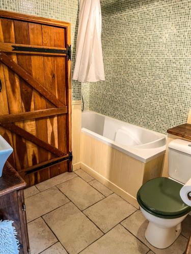 une salle de bain avec toilettes et baignoire avec porte dans l'établissement Le Petit Nid, à Romagne
