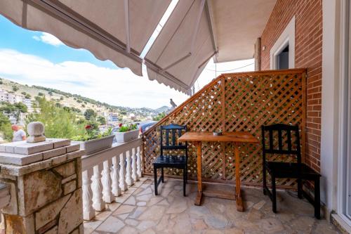 een balkon met een houten tafel en twee stoelen bij Vila Basho in Sarandë