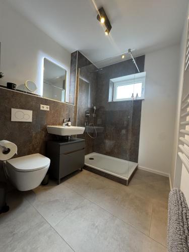 a bathroom with a shower and a toilet and a sink at FILDER quartett Apartmenthotel in Filderstadt