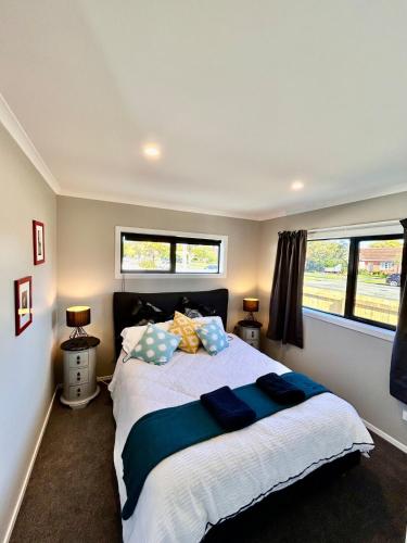 a bedroom with a large bed and two windows at The heart of Palmerston North in Palmerston North