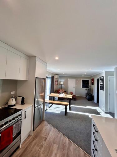 a kitchen and living room with white cabinets and a table at The heart of Palmerston North in Palmerston North