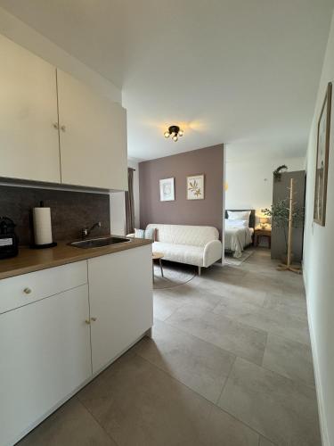 a kitchen with white cabinets and a living room at FILDER quartett Apartmenthotel in Filderstadt