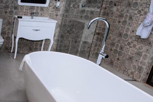 a bathroom with a tub and a sink and a shower at Escapade Lux Guesthouse in Gaborone