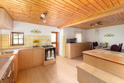 a large kitchen with wooden cabinets and a wooden ceiling at Sunflower House with Jacuzzy and Sauna in Vitanje
