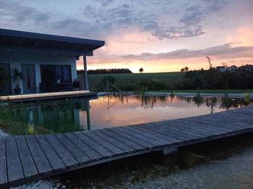 a house with a dock in the water at sunset at Schnatterhof in Lambrechten