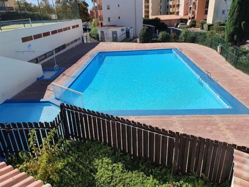 une grande piscine bleue à côté d'une clôture dans l'établissement Reflet du Sud - 4pers - Histoire de cles, au Cap d'Agde