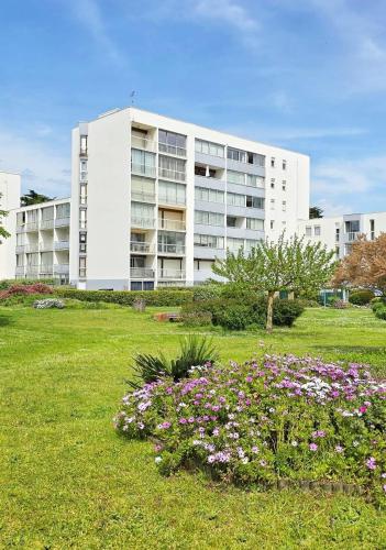 un grand bâtiment blanc avec des fleurs dans un champ dans l'établissement Grande Plage, Quiberon, 2 bedrooms, à Quiberon