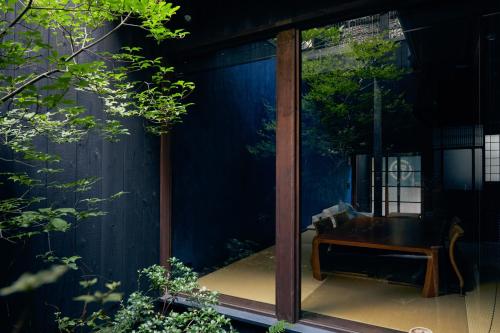 a glass house with a wooden table and a bench at YADORU KYOTO HANARE Mizunoe No Yado in Kyoto