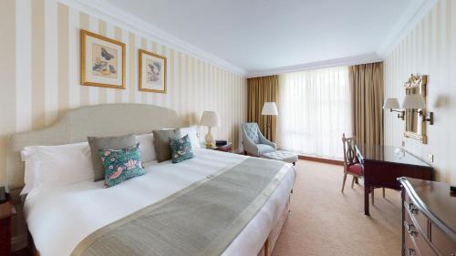 a hotel room with a large bed and a desk at Cheval Thorney Court at Hyde Park in London