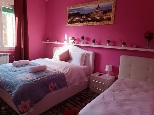 a bedroom with pink walls and a bed with pillows at Locazione turistica 2 in Tessera