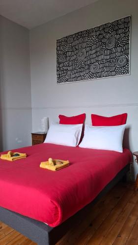 a red bed with two towels on top of it at Le Clos'art in Vinassan