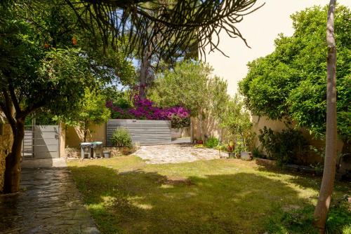 a garden with trees and purple flowers in the background at Agali 2 maizonette front of the sea in Akrogiali