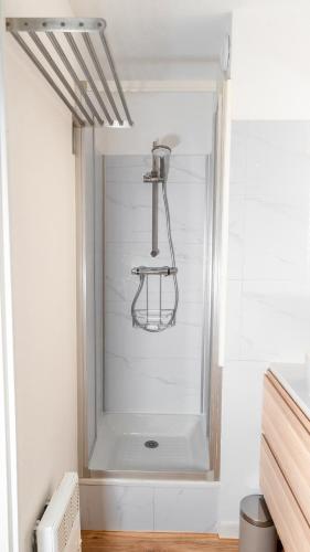 La salle de bains est pourvue d'une douche et d'un mur blanc. dans l'établissement Le Corsaire - Séjour Relaxant, Plage & Piscine, à Carqueiranne