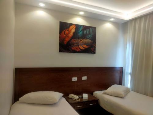 a hotel room with two beds and a painting on the wall at Salma Hotel Cairo in Cairo