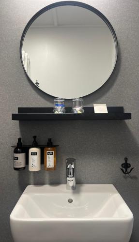 a bathroom sink with a round mirror above it at Aurora Lodge Hotel in Hvolsvöllur