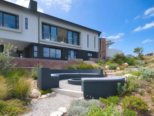 a house with two benches in front of it at Fynbos Hill Luxury Accommodation in Agulhas