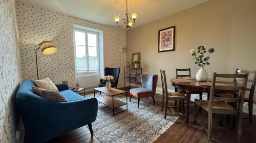 Una sala de estar con un sofá azul y una mesa. en Maison Belle Vie, en Saint-Symphorien-de-Marmagne