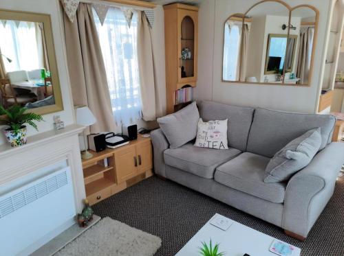 a living room with a couch and a mirror at Charming Caravan To Hire At Breydon Water Holiday Park In Norfolk Ref 10003Tc in Belton