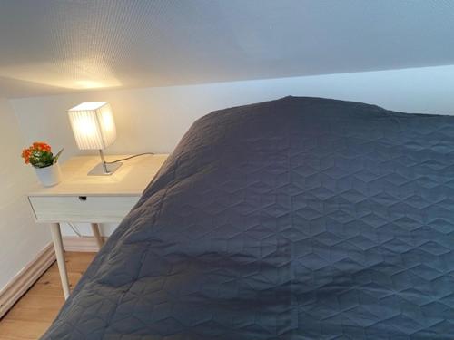 a bedroom with a bed and a table with a lamp at Dejlig gårdhave 5 soveværelser in Harboør