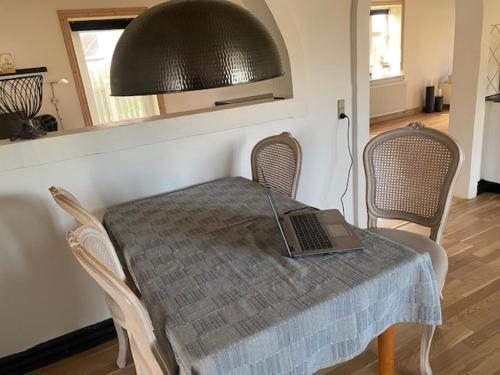 a laptop computer sitting on a table with chairs at Dejlig gårdhave 5 soveværelser in Harboør