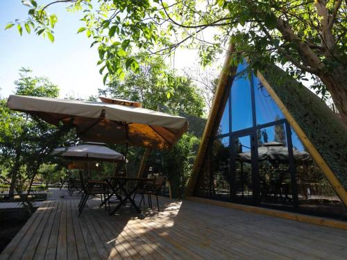 a wooden deck with an umbrella and tables and chairs at turpan Ah Fanti Village in Turfan