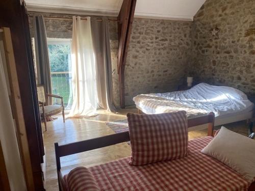 a bedroom with two beds and a couch and a window at gite meymac in Meymac