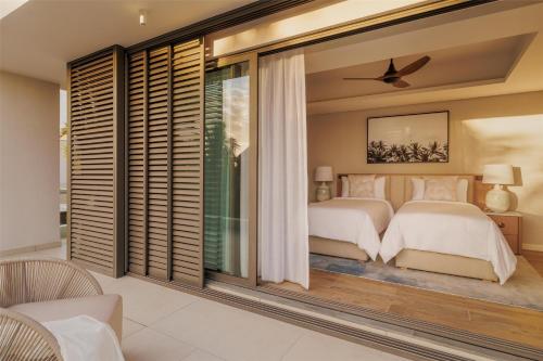 a bedroom with two beds and a large window at One&Only Le Saint Géran, Mauritius in Belle Mare