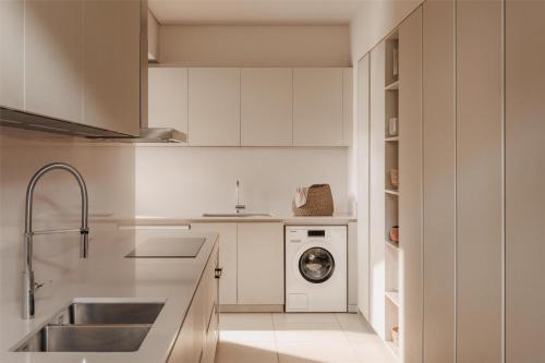 a kitchen with white cabinets and a washer and dryer at One&Only Le Saint Géran, Mauritius in Belle Mare