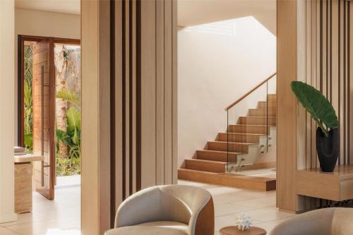 a living room with a staircase and a chair at One&Only Le Saint Géran, Mauritius in Belle Mare