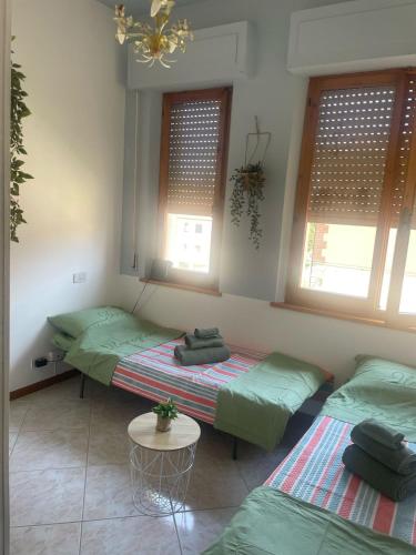 two beds in a room with a table and windows at Casa di Isma in San Quirico dʼOrcia