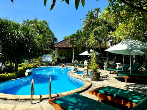 a pool at a resort with chairs and an umbrella at Coral Bay Bungalows Amed Bali in Amed