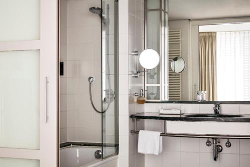 a bathroom with a shower and a sink and a mirror at The Mandala Berlin, a Member of Design Hotels in Berlin