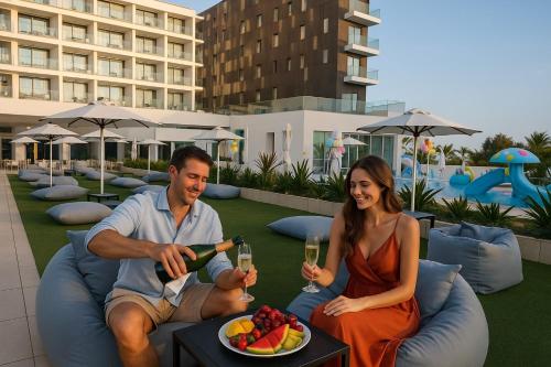 a man and a woman sitting on a couch with a plate of fruit at Chrysomare Beach Hotel & Resort in Ayia Napa