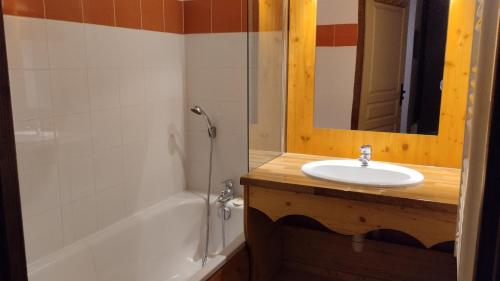 un bagno con un lavandino, una vasca e uno specchio di Hameau 4 106 - SPA & PISCINE appartement 6 pers a Orelle