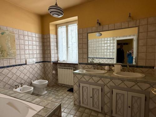 a bathroom with two sinks and a toilet and a mirror at Rustico Near Outlet - Free Parking and Near Gavi in Castelletto d'Orba