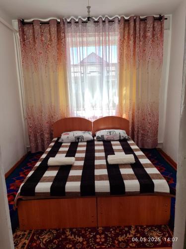 a bed in a bedroom with a window with curtains at Guest house Liliya in Kochkor