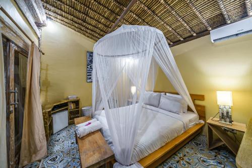 a bedroom with a bed with a mosquito net at Villa Matahari - Cute 1 bdr villa with private pool in Gili Meno