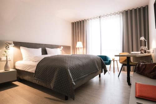 Habitación de hotel con cama, escritorio y habitación en Maximilians Boutique-Hotel Landau, en Landau in der Pfalz