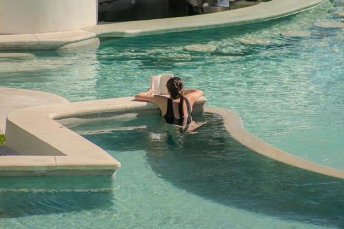 a woman sitting in the water in a swimming pool at ME Cabo by Meliá in Cabo San Lucas