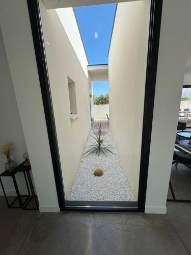 une pièce avec une fenêtre avec une plante au milieu dans l'établissement Villa Noam Haut Standing 220m2, à Beauvoisin