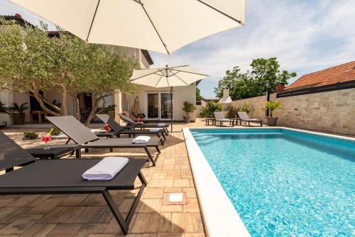 - Piscina con tumbonas y sombrilla en Villa La Aurora ZadarVillas, en Murvica