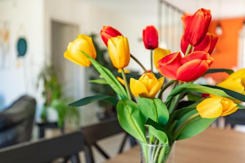 a vase filled with red and yellow flowers on a table at La Maison Tulipe à Plaisance du Touch in Plaisance-du-Touch
