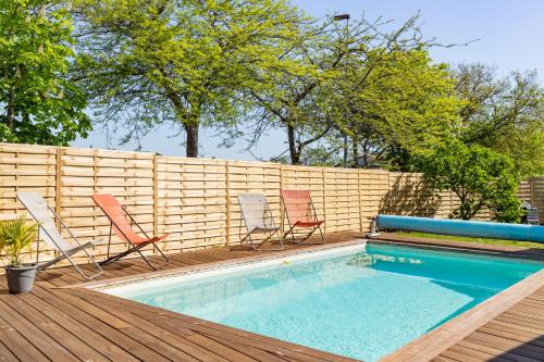 a swimming pool with two chairs and a fence at La Maison Tulipe à Plaisance du Touch in Plaisance-du-Touch