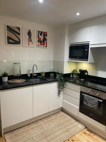 a kitchen with white cabinets and a microwave at New 1 Bed Apartment 12 mins to Central London and Gatwick Airport in Croydon