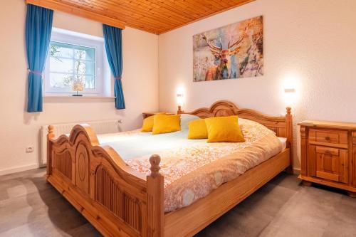 a bedroom with a wooden bed with yellow pillows at Landhaus Schnorrenberg, Wellness & Nature in Hellenthal